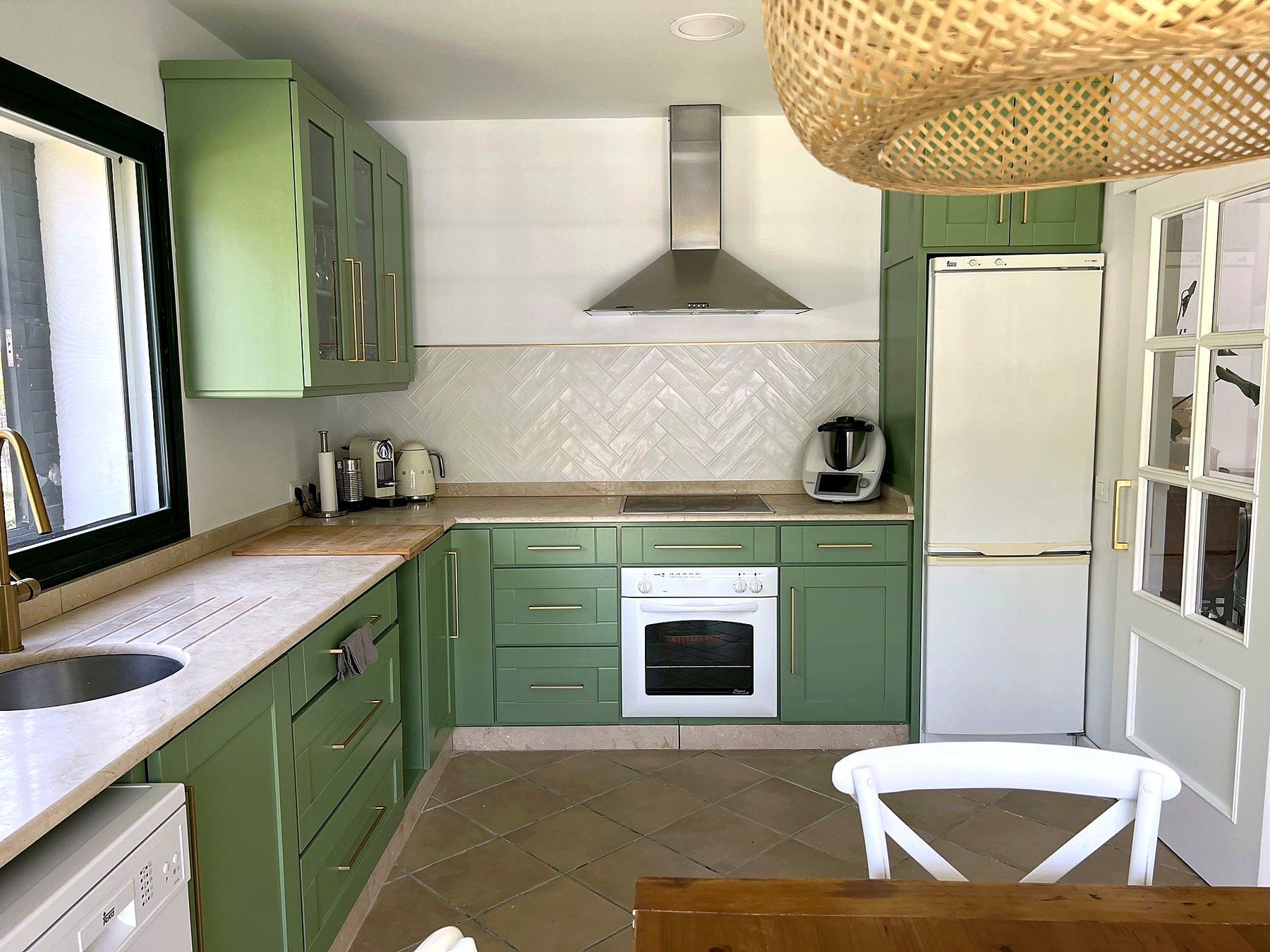 Cocina en L con encimera de mármol, campana, horno y azulejo en espiga