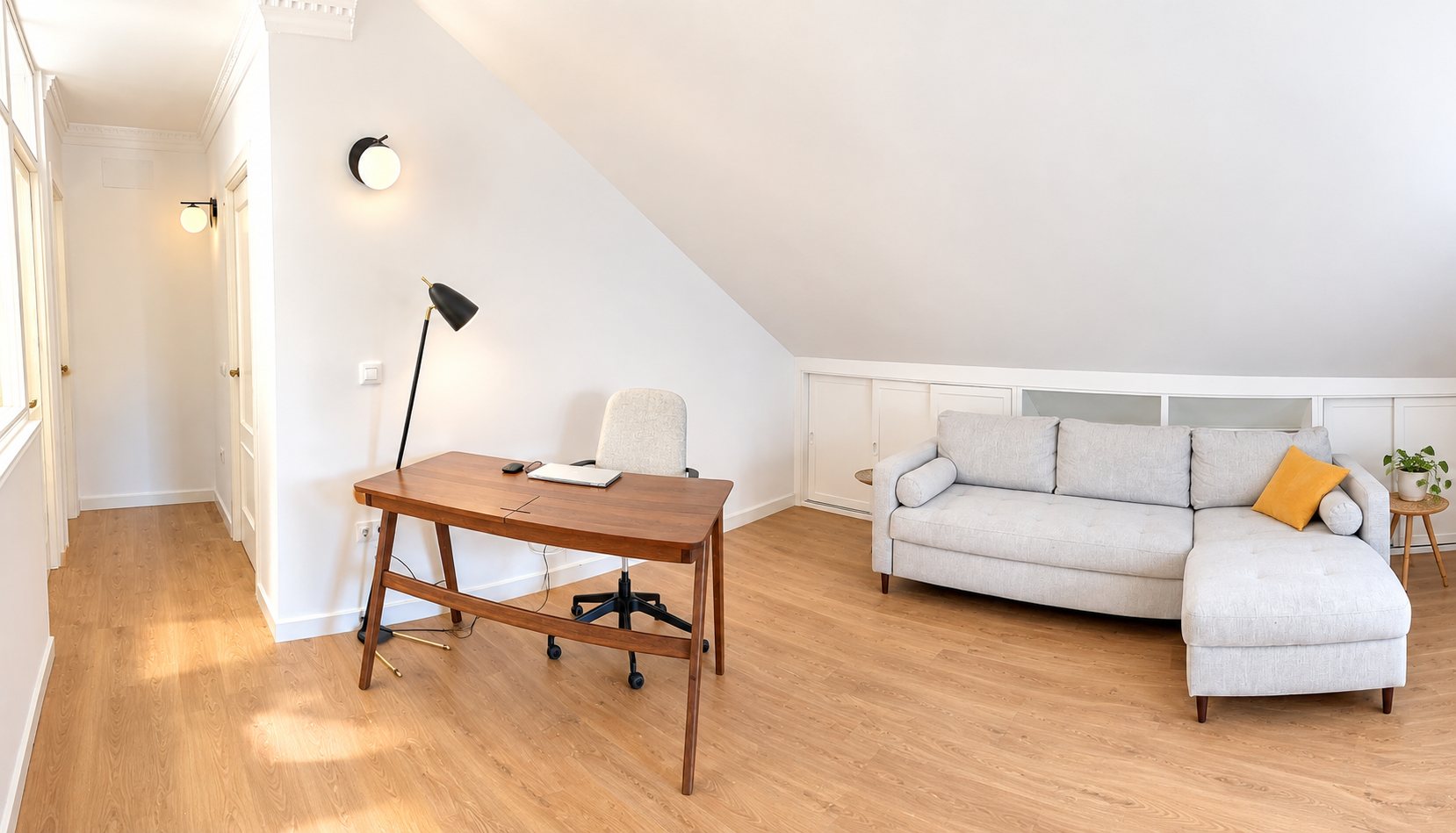 Estudio abuhardillado con escritorio de madera y sofá chaise longue