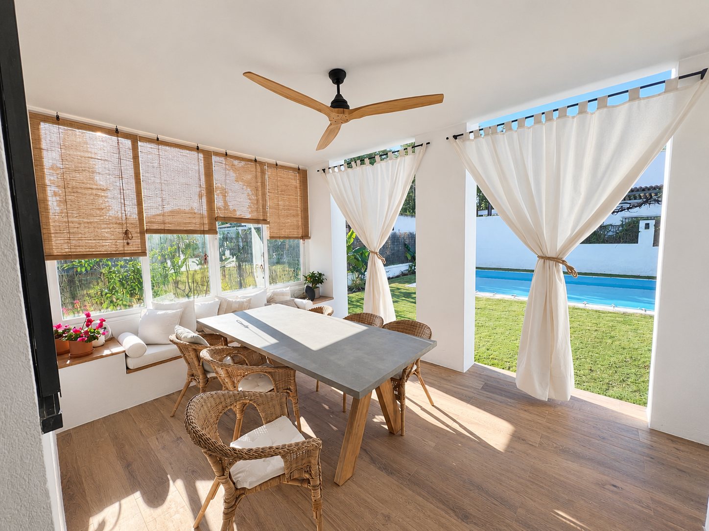 Porche cubierto con mesa de comedor, ventilador de techo y vistas a la piscina