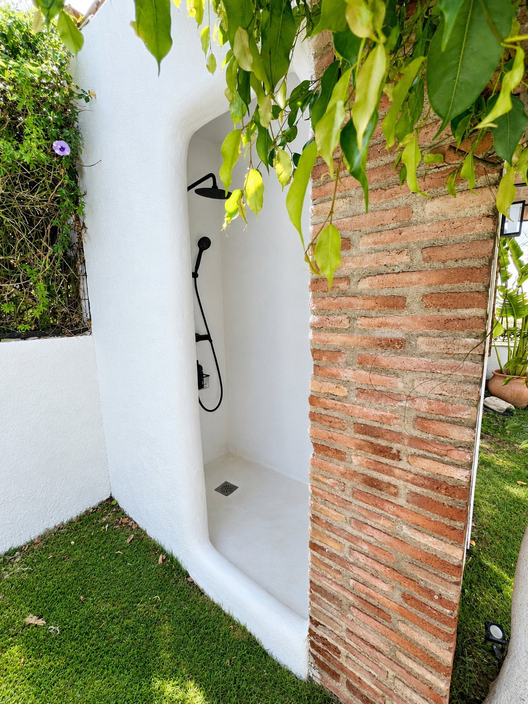 Ducha exterior de obra blanca junto a la piscina