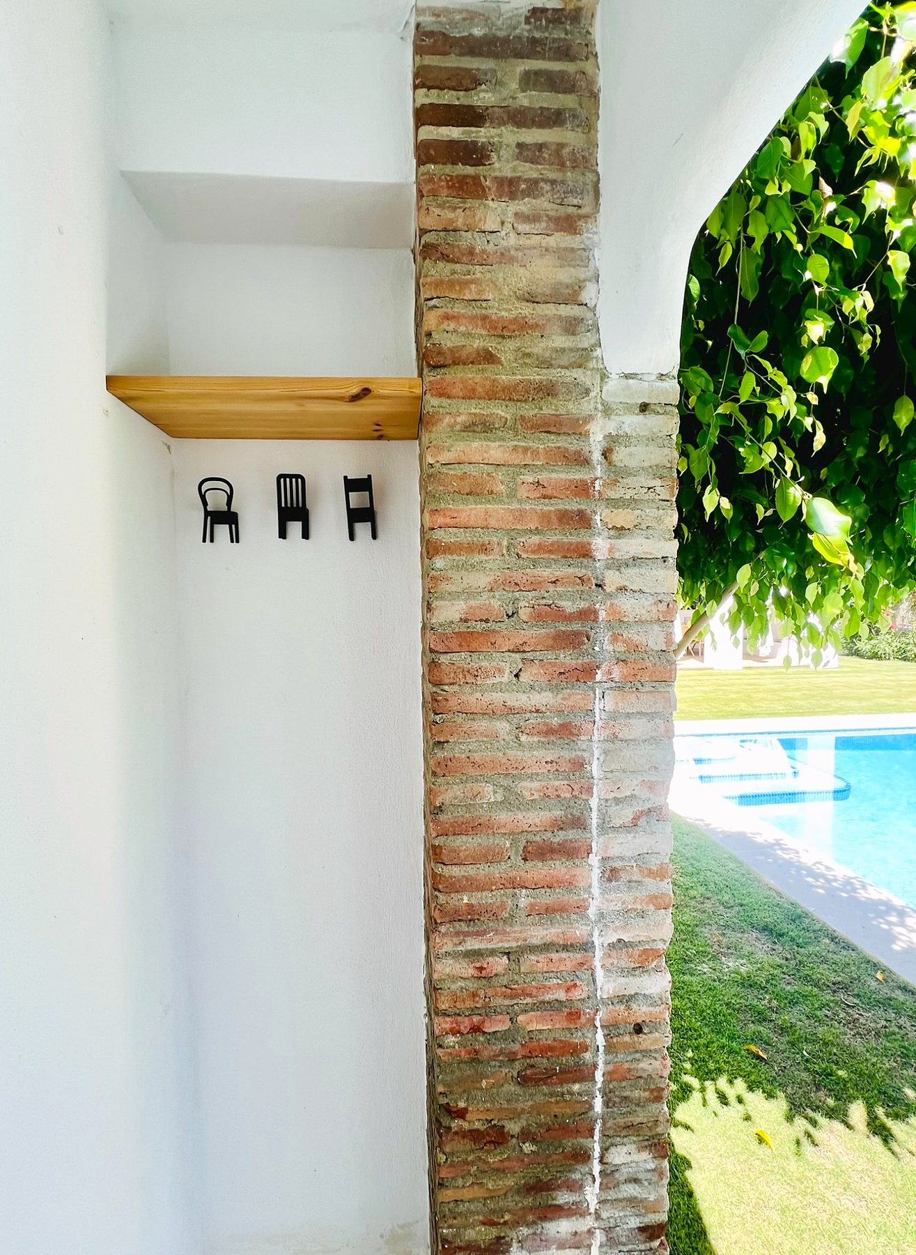 Rincón del porche con balda de madera y colgadores en forma de silla